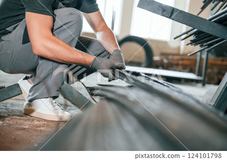 Measuring lenght of metal pieces. Man in uniform is in workstation developing details of agriculture technique 124101798