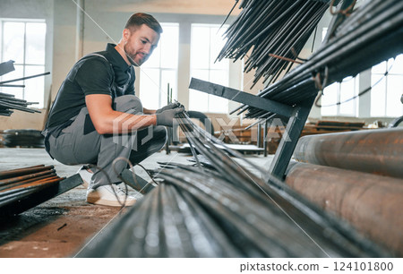 Taking metal pieces. Man in uniform is in workstation developing details of agriculture technique Taking metal pieces. Man in uniform is in workstation developing details of agriculture technique 124101800