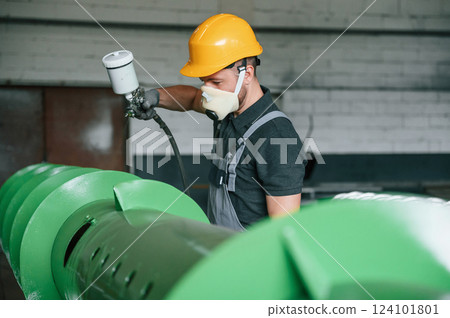 In protective mask. Painting details. Man in uniform is in workstation developing details of agriculture technique In protective mask. Painting details. Man in uniform is in workstation developing details of agriculture technique 124101801