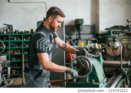 Turning wheel. Man in uniform is in workstation developing details of agriculture technique 124101822