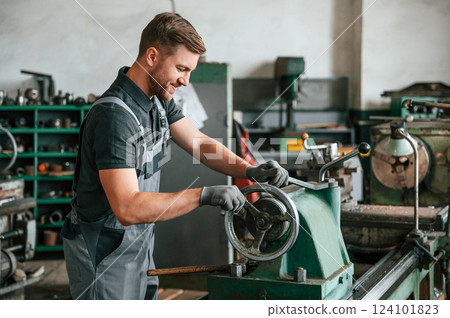 Turning wheel. Man in uniform is in workstation developing details of agriculture technique 124101823
