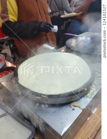 Frying pancake. Making pancakes with lot of steam outdoors. Persona preparing large round pancake on frying pan close-up. Cooking food on street. Cooking street food fried dough. Festivities. 124102327