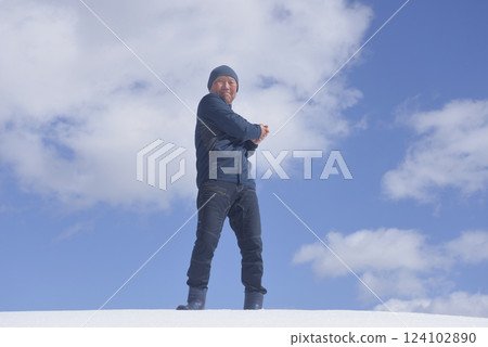 An old man stretching under the blue sky on a sunny day in a snowy country 124102890