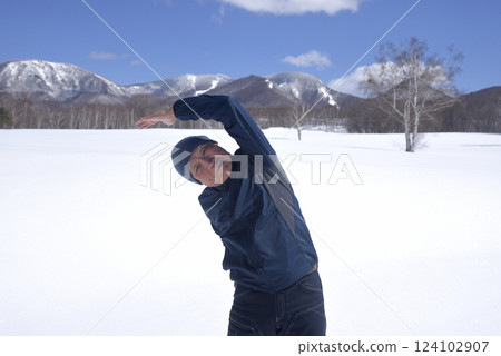 An old man stretching under the blue sky on a sunny day in a snowy country 124102907