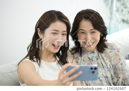 A stylish mother and daughter looking at a smartphone together A stylish mother and daughter looking at a smartphone together 124102987