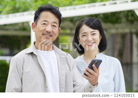中年夫婦在戶外拿著智慧型手機 124103015