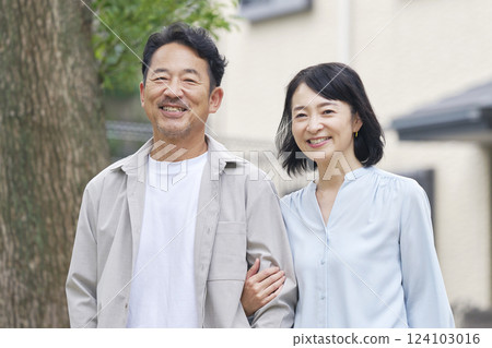 Middle-aged couple walking arm in arm outdoors 124103016