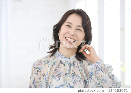A smiling middle-aged woman wearing a floral blouse A smiling middle-aged woman wearing a floral blouse 124103071