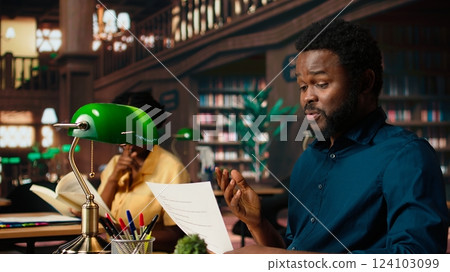 African american college student feels frustrated and overwhelmed with the learning struggles, worried depressed pupil struggling to memorize information from class notes. Camera A. 124103099