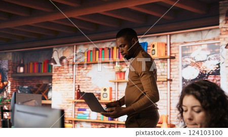 Startup employee coming at work with notebook, conducting code review to fix bugs, identifying technical issues. Artificial intelligence company worker arriving in office with laptop, camera A 124103100