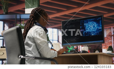Teleworking programmer using computer for artificial intelligence computing through self learning algorithms. Remote worker working with AI deep neural networks on desktop PC, camera B 124103183