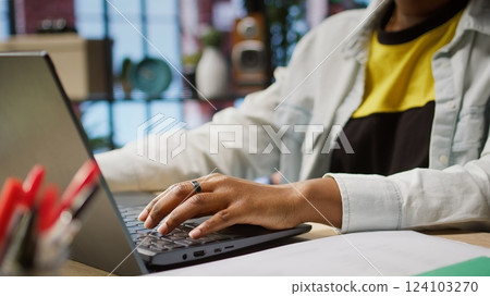 Freelancer in home office sitting at desk and typing on laptop keyboard. Close up of remote worker using electronic device to do customers relations job online, answering inquiries, camera A 124103270