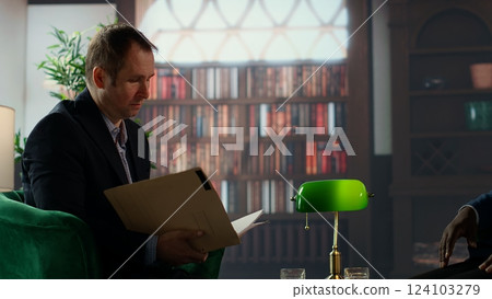 Team of intelligence agents reviewing critical documents in a vintage safe house, highlighting professionalism to solve a mission of national government importance. Top secret tasks. Camera B. 124103279