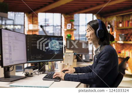 Senior programmer coding advanced AI algorithm in startup office, refining machine learning models to enhance automation, wearing headphones. Asian CTO manager listening music and coding Senior programmer coding advanced AI algorithm in startup office, refining machine learning models to enhance automation, wearing headphones. Asian CTO manager listening music and coding 124103324