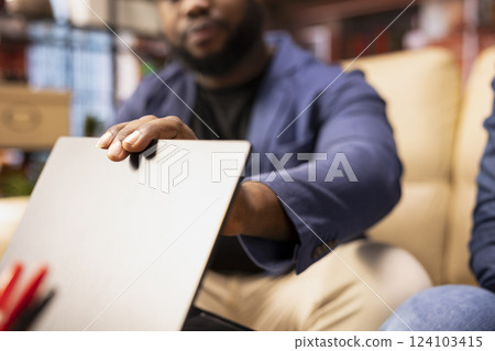 Black man prioritizes self care and mental wellbeing for his wife by closing the laptop and urging for a break. Supportive conversation helps them recharge and reduce stress in living room. Close up. 124103415