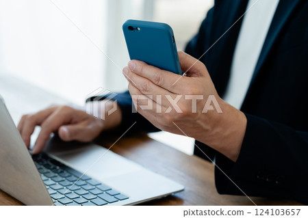 A man who operates a computer and a smartphone A man who operates a computer and a smartphone 124103657