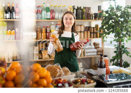 Teen girl seller stands in trading hall of store with goods in hand 124105688