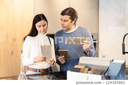 Couple chooses together the material from which they will order furniture and kitchen set Couple chooses together the material from which they will order furniture and kitchen set 124105801