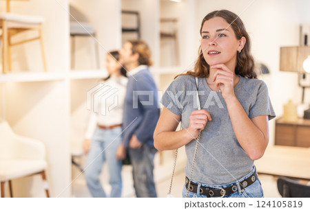 Young woman choosing decoration in furniture salon Young woman choosing decoration in furniture salon 124105819