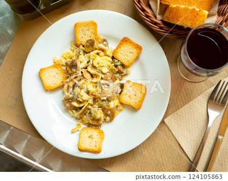 Omelette with mushrooms and spring garlic served with crispy croutons on white plate. 124105863