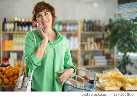 Female shopper talking on smartphone while shopping in grocery supermarket 124105866