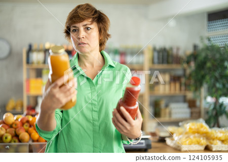 Grocery shopping at supermarket - woman chooses juice, tomato, grapefruit or peach 124105935