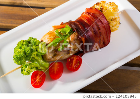 Roasted quail wrapped in ham with vegetables 124105943