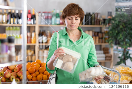 Adult woman choosing mushrooms in grocery store Adult woman choosing mushrooms in grocery store 124106116