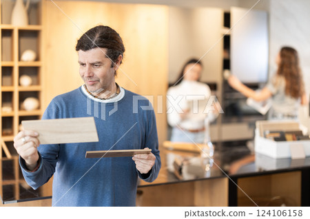 Man standing in furniture salon with examples of wood Man standing in furniture salon with examples of wood 124106158