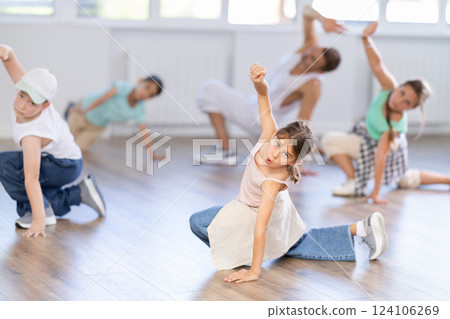 Cheerful sports preteen girls and boys hip hop dancers doing dance workout on floor with male trainer during group class Cheerful sports preteen girls and boys hip hop dancers doing dance workout on floor with male trainer during group class 124106269
