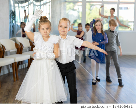 Little children in elegant dresses practicing waltz dance in school hall 124106481