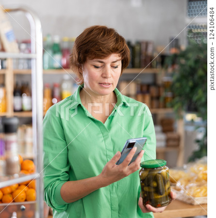 Adult woman scanning qr code of pickled cucumbers Adult woman scanning qr code of pickled cucumbers 124106484