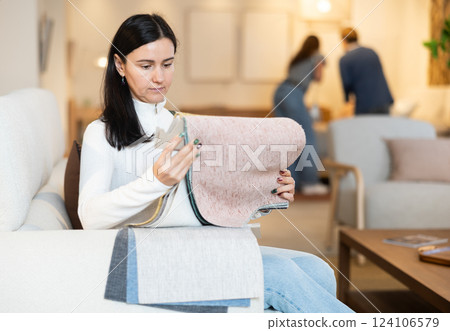 European woman looks at upholstery fabric in a store 124106579