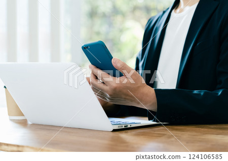 A man who operates a computer and a smartphone 124106585