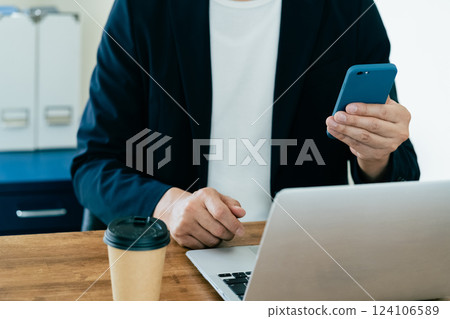 一個操作電腦和智能手機的人 一個操作電腦和智能手機的人 124106589