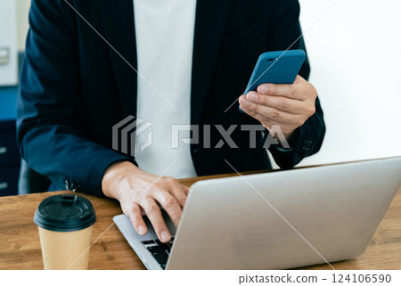 A man who operates a computer and a smartphone 124106590