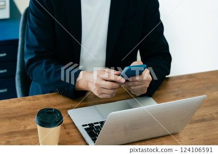 A man who operates a computer and a smartphone 124106591