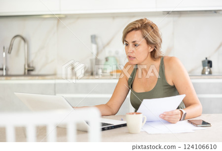 Middle-aged woman working on notebook in the kitchen 124106610