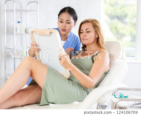 Cosmetologist examining face of woman and planning face lifting procedures Cosmetologist examining face of woman and planning face lifting procedures 124106709