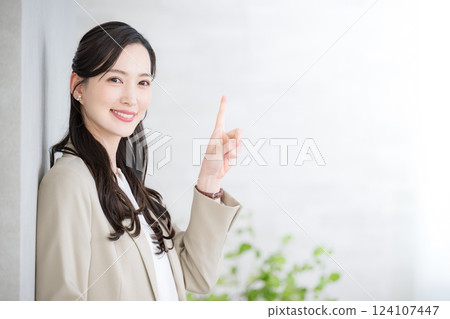 Beautiful woman in a suit holding a laptop computer looking at the camera and pointing at something. Job change, recruitment, human resources, consulting Beautiful woman in a suit holding a laptop computer looking at the camera and pointing at something. Job change, recruitment, human resources, consulting 124107447