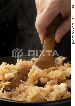 Put the freshly cooked, steaming octopus rice into a bowl with a rice spoon. 124107900