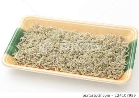 Dried small sardines in a plastic tray on a white background 124107989