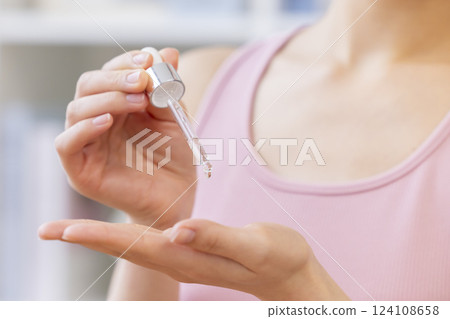 美容圖片：一位女士將美容精華液滴在手上 124108658