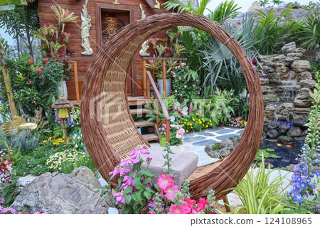 Garden With Unique Wicker Chair and Colorful Flowers Garden With Unique Wicker Chair and Colorful Flowers 124108965