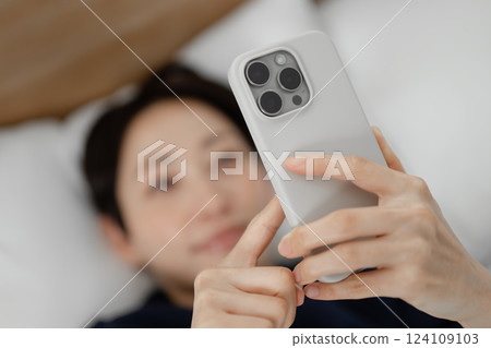 A woman watching a smartphone in bed A woman watching a smartphone in bed 124109103