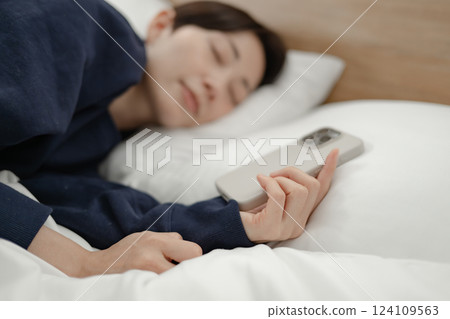 Woman, smartphone, falls asleep 124109563