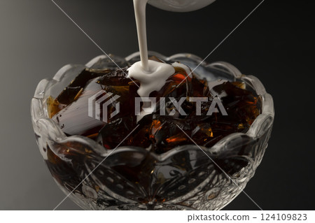 將牛奶倒入玻璃碗中的冷咖啡果凍中 將牛奶倒入玻璃碗中的冷咖啡果凍中 124109823