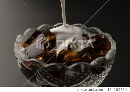 Pour milk over cold coffee jelly in a glass bowl 124109824