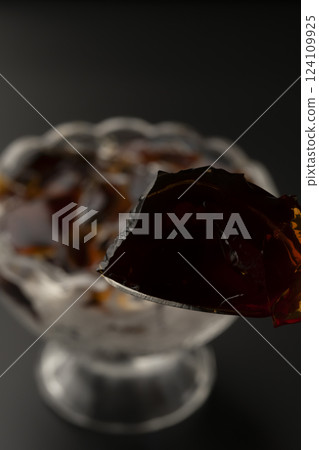 用湯匙從玻璃碗裡舀出冷咖啡果凍 用湯匙從玻璃碗裡舀出冷咖啡果凍 124109925