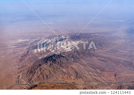 Snow-capped mountain ranges in China. Tien Shan or the Himalayas, beautiful mountains from a high altitude view from an airplane geology. 124111443